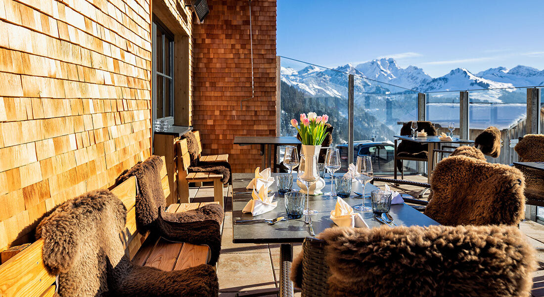 Sonnenterrasse des Hotels Sonnasita im Winter, gemütlich eingerichtet mit Schaffellen.